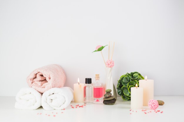 Spa products and illuminated candles on white tabletop