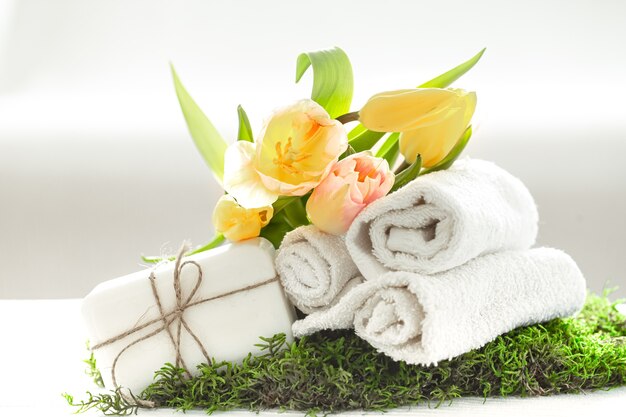 Натюрморт спа с натуральным мылом, полотенцами и желтыми тюльпанами на светлом размытом фоне копией пространства.