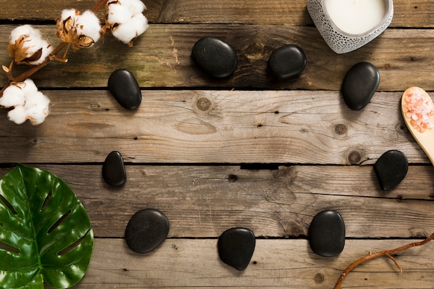 Spa stones with cotton flowers and green leaf on wooden table