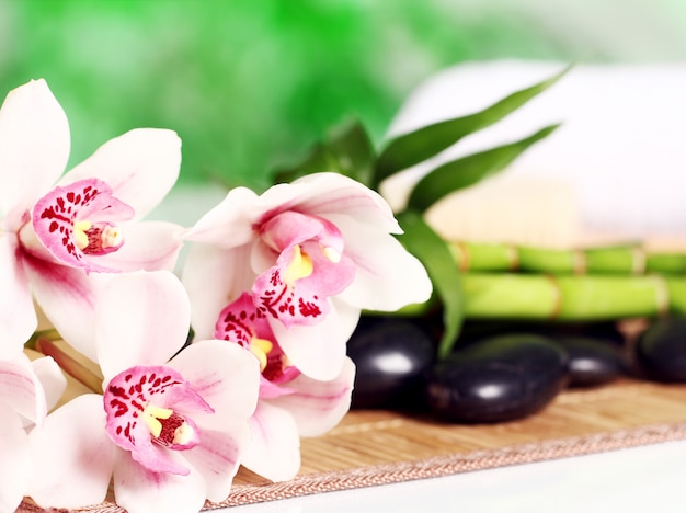 Spa and wellness, massage stones and flowers on wooden tablecloth