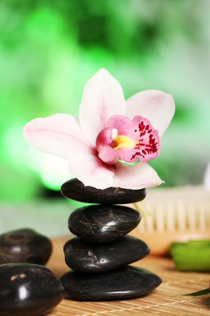 Spa and wellness, massage stones and flowers on wooden tablecloth