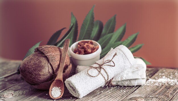 Spa and wellness setting with flowers and towels. Bright composition on brown table with tropical flowers. Dayspa nature products with coconut