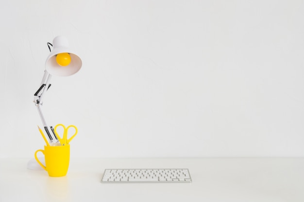 Free photo spacious workplace with yellow mug and keyboard