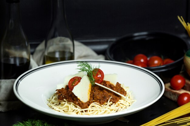 Spaghetti bolognese garnished with cherry tomatoes and parmesan slices