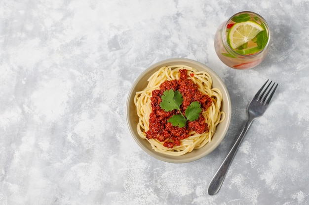 Spaghetti bolognese and lemonade on grey concrete 