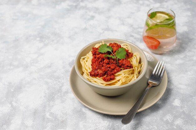 Spaghetti bolognese and lemonade on grey concrete 