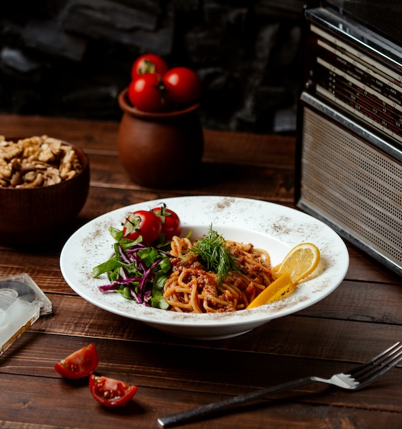 Spaghetti bolognese with tomato and lemon slices