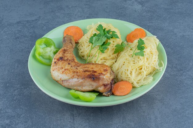 Spaghetti and grilled leg on green plate.