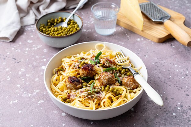 Spaghetti pasta with meatballs in cream sauce on a plate on a background of stone or concrete