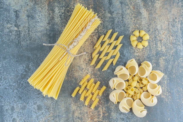 Foto gratuita spaghetti, penne, fusilli e pasta ammucchiata, sullo sfondo di marmo.