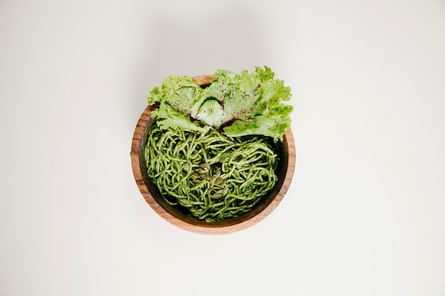 Спагетти в соусе песто с листьями зеленого салата.