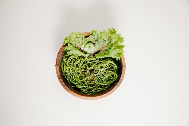 Spaghetti in pesto sauce with green lettuce leaf.