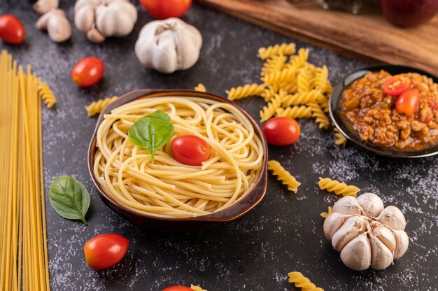 Spaghetti saute in a gray plate with tomatoes and basil