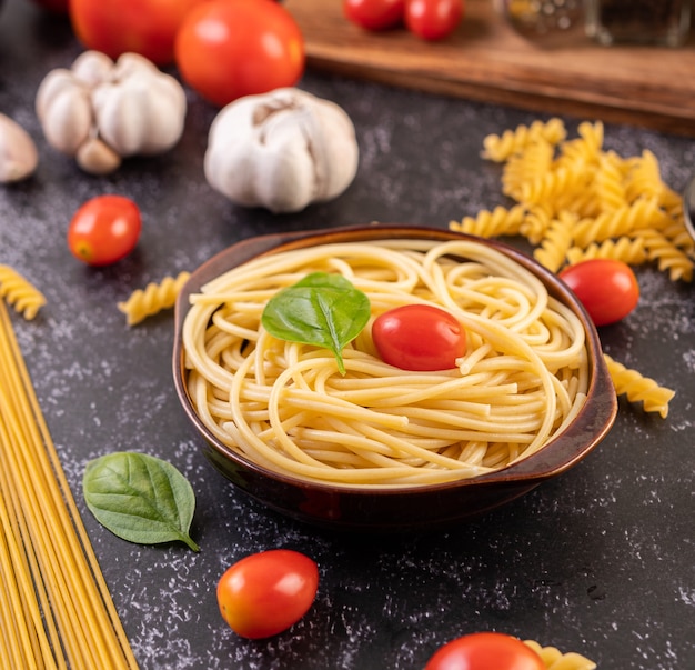 Spaghetti saute in a gray plate with tomatoes and basil