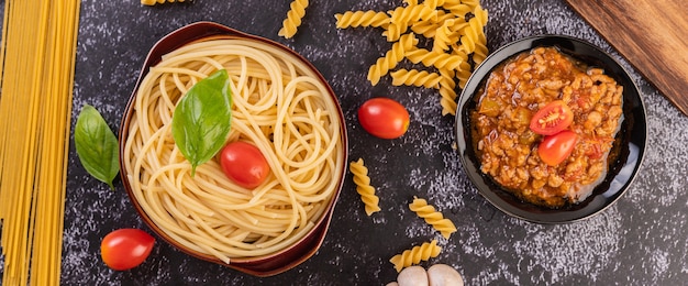 Spaghetti saute in a gray plate with tomatoes and basil