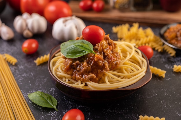 Spaghetti saute in a gray plate with tomatoes and basil