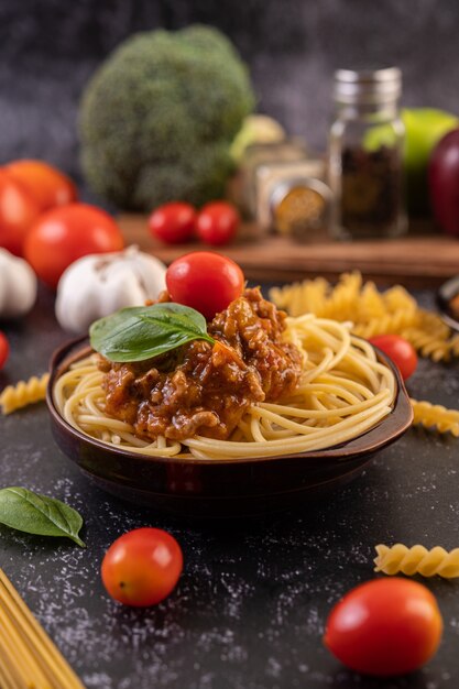 Spaghetti saute in a gray plate with tomatoes and basil