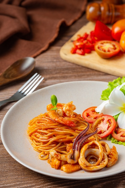 Спагетти с морепродуктами в томатном соусе, украшенные красивыми ингредиентами.