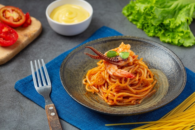 Спагетти с морепродуктами в томатном соусе, украшенные красивыми ингредиентами.