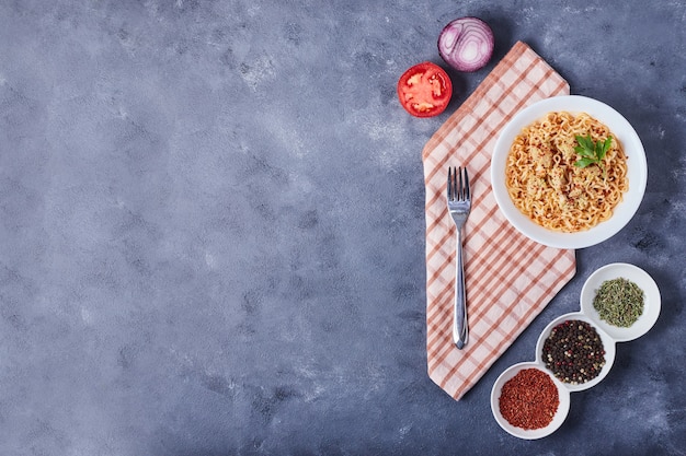 Spaghetti in a white plate with spices around.