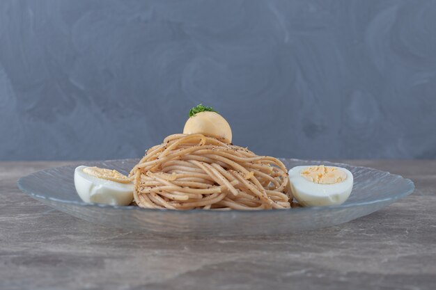 Spaghetti with boiled eggs on glass plate. 