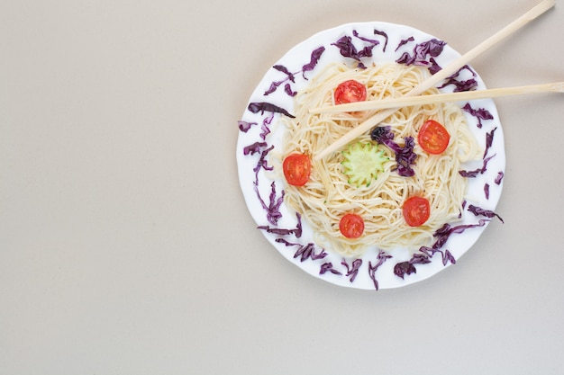 白いプレートにキャベツとトマトのスライスとスパゲッティ