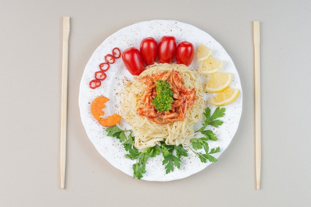 白い皿に刻んだ鶏肉と野菜のスパゲッティ