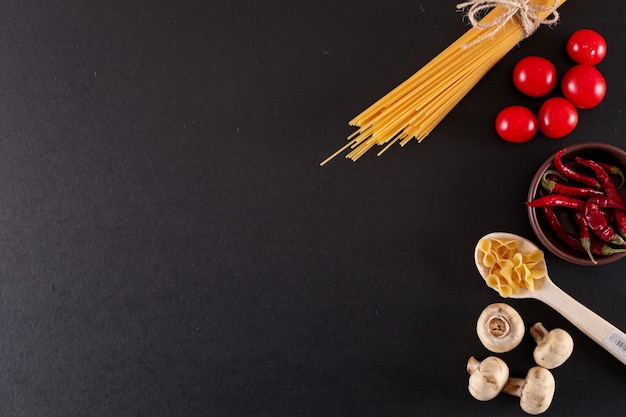 spaghetti with dried red pepper mushroom top view with copy space on black surface