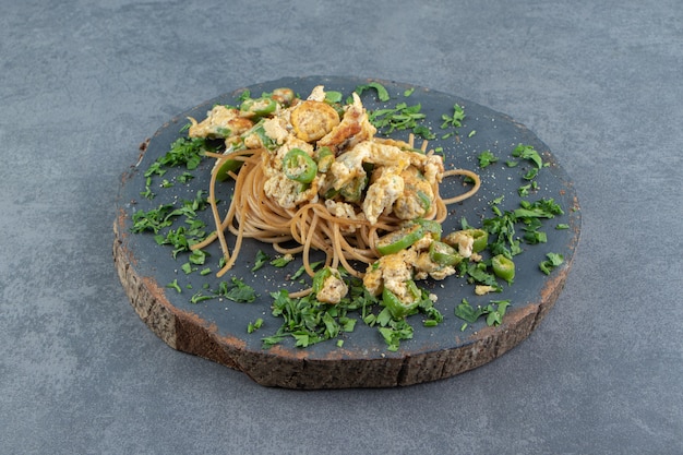 Spaghetti with fried egg on wood piece.