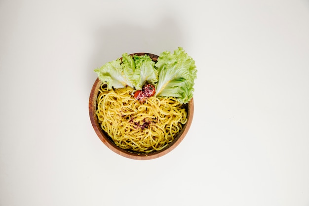 Spaghetti with lettuce inside wooden bowl.