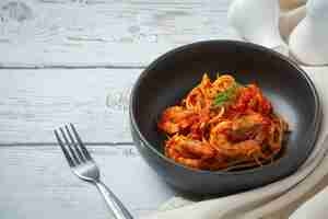 Foto gratuita spaghetti con gamberetti in salsa di pomodoro su fondo di legno bianco