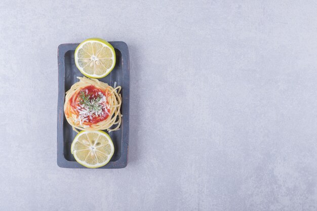 Spaghetti with tomato pasta and lemons on dark plate. 