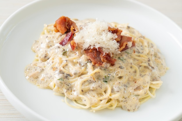 Спагетти с трюфельным сливочным соусом и грибами на тарелке Premium Фотографии
