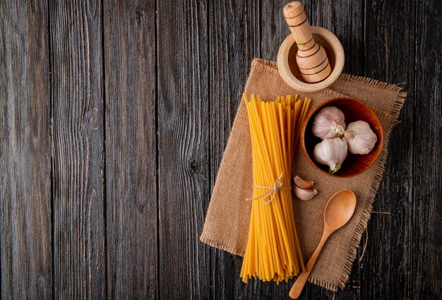 Spaghetti on the wooden background garlic spoon mortartop view copy space