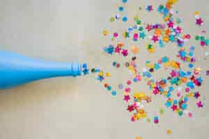 Free photo spangles scattered from blue bottle on table