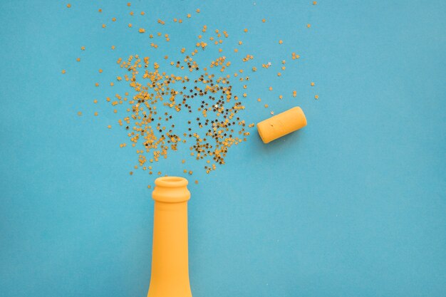 Spangles scattered from bottle on table 