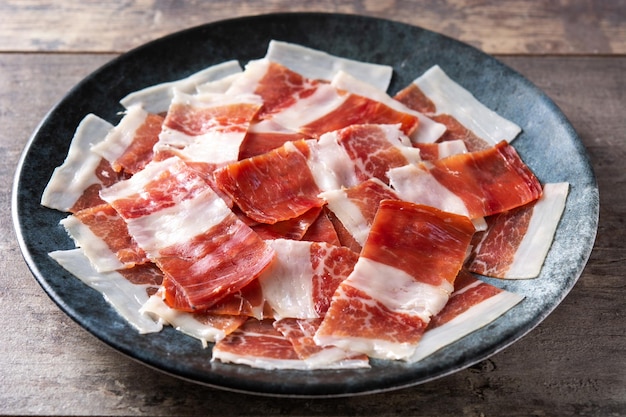 Foto gratuita piatto di fette di prosciutto serrano spagnolo sul tavolo di legno