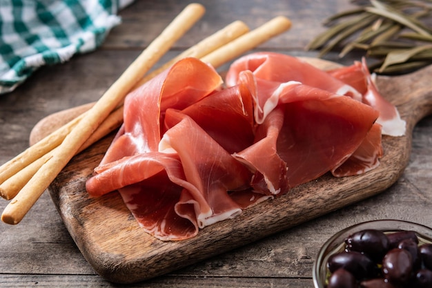 Spanish serrano ham with olives and breadstick