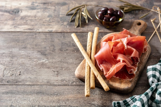 Foto gratuita prosciutto spagnolo serrano con olive e grissino