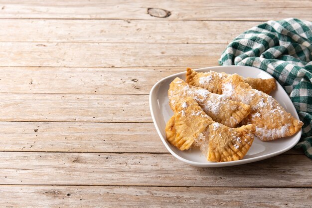 Spanish sweet stuffed pastry filled with angel hair on wooden table.