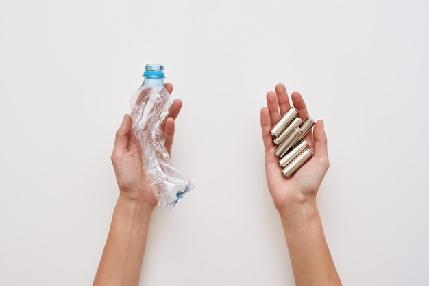 Sparate your trash. two human hands are holding plastic and batteries isolated.