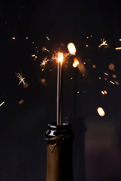 Free photo sparkler in champagne bottle at night