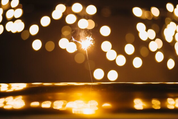 Sparkler and lights over reflective surface