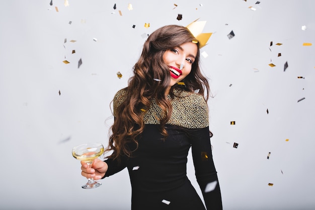 Sparkling confetti, positive emotions of excited amazing girl with long curly hair, yellow crown having fun on white space.