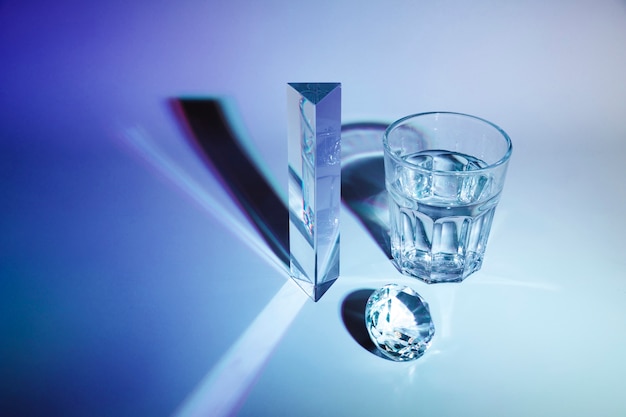 Sparkling diamond; prism; glass of water with shadow on dark blue background