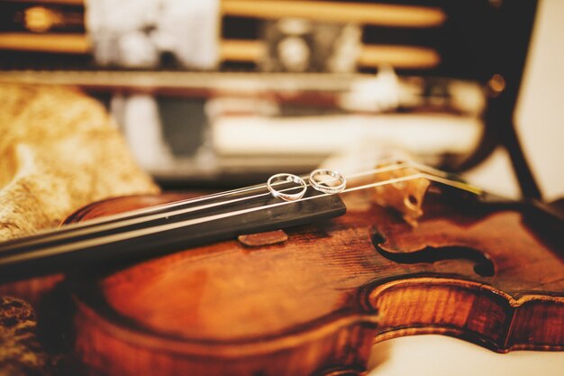 輝く結婚指輪がバイオリンの弦の上に横たわっています