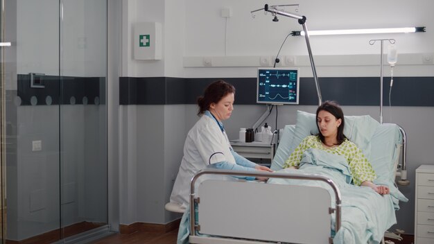 Specialist doctor putting oximeter checking pulse talking with sick woman