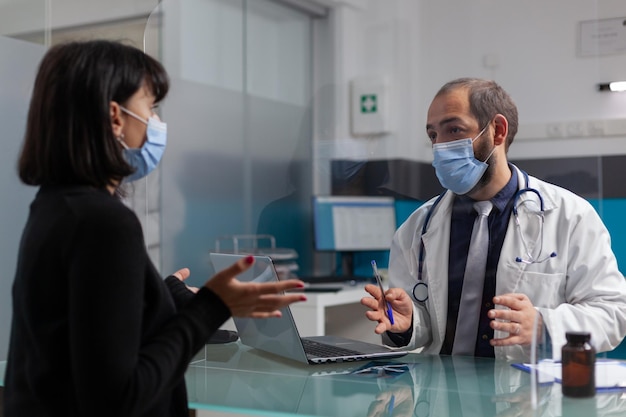 Free photo specialist and person discussing about health at checkup appointment in cabinet. medic talking to woman about prescription medicine and treatment during coronavirus pandemic. medical visit