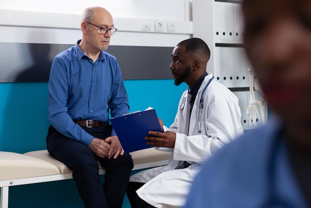 Specialist physician doctor explaining sickness expertise to retired old man discussing healthcare treatment in hospital office. Senior patient having medical appointment. Medicine concept