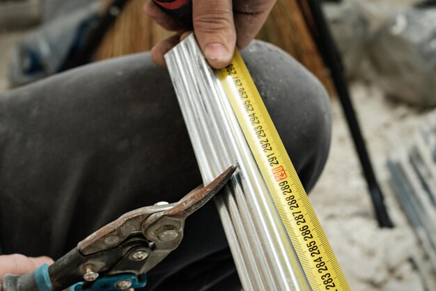 Specialist prepares steel profiles for drywall, close-up, selective focus. Preparing for the installation of the frame of the ceiling profile system. Renovation and refurbishment